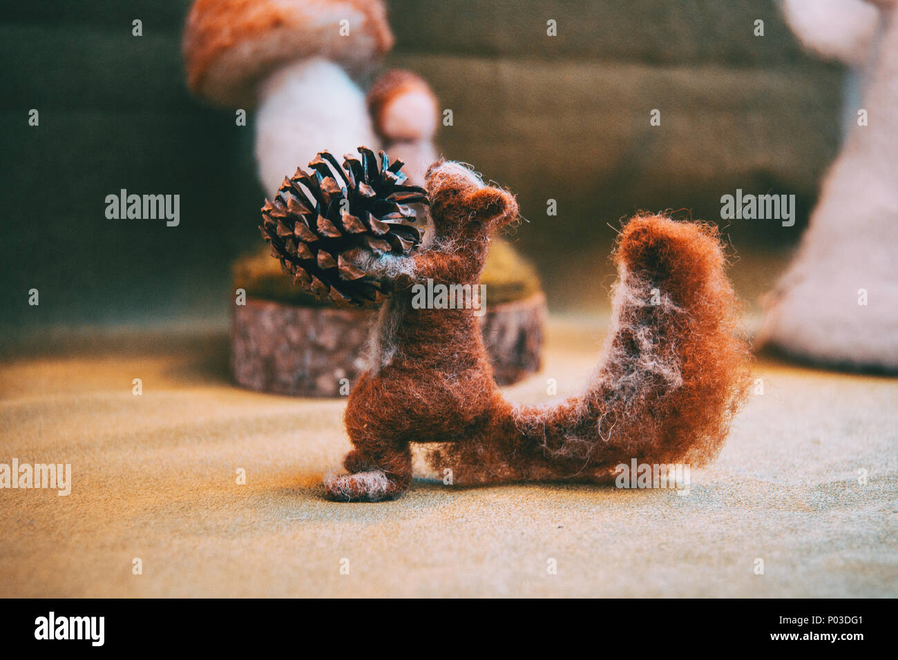 Felt brown squirrel holding a pine cone Stock Photo