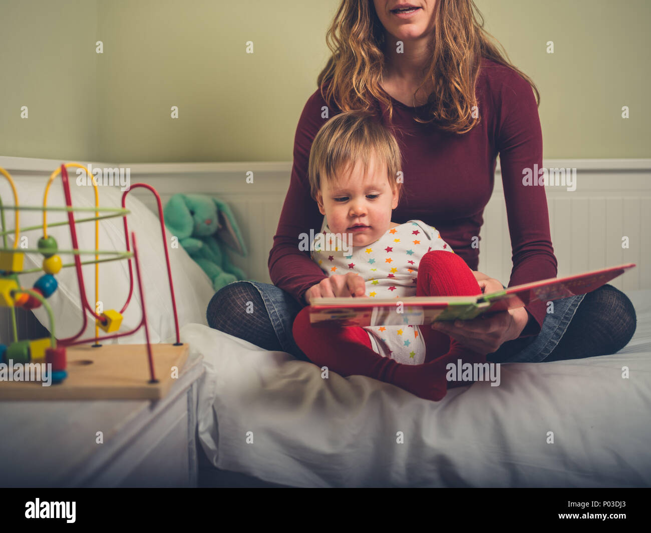A young mother is reading a bedtime story to her little boy Stock Photo