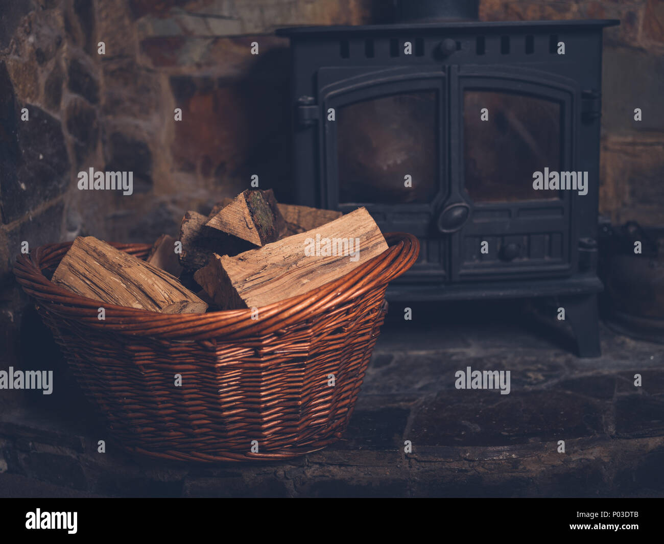 A basket full of firewood by a log burner Stock Photo