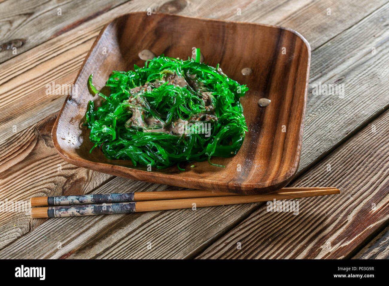 Chukka Salad with walnut sharp sauce in a wooden dish on a wooden background. Oriental sea food Stock Photo