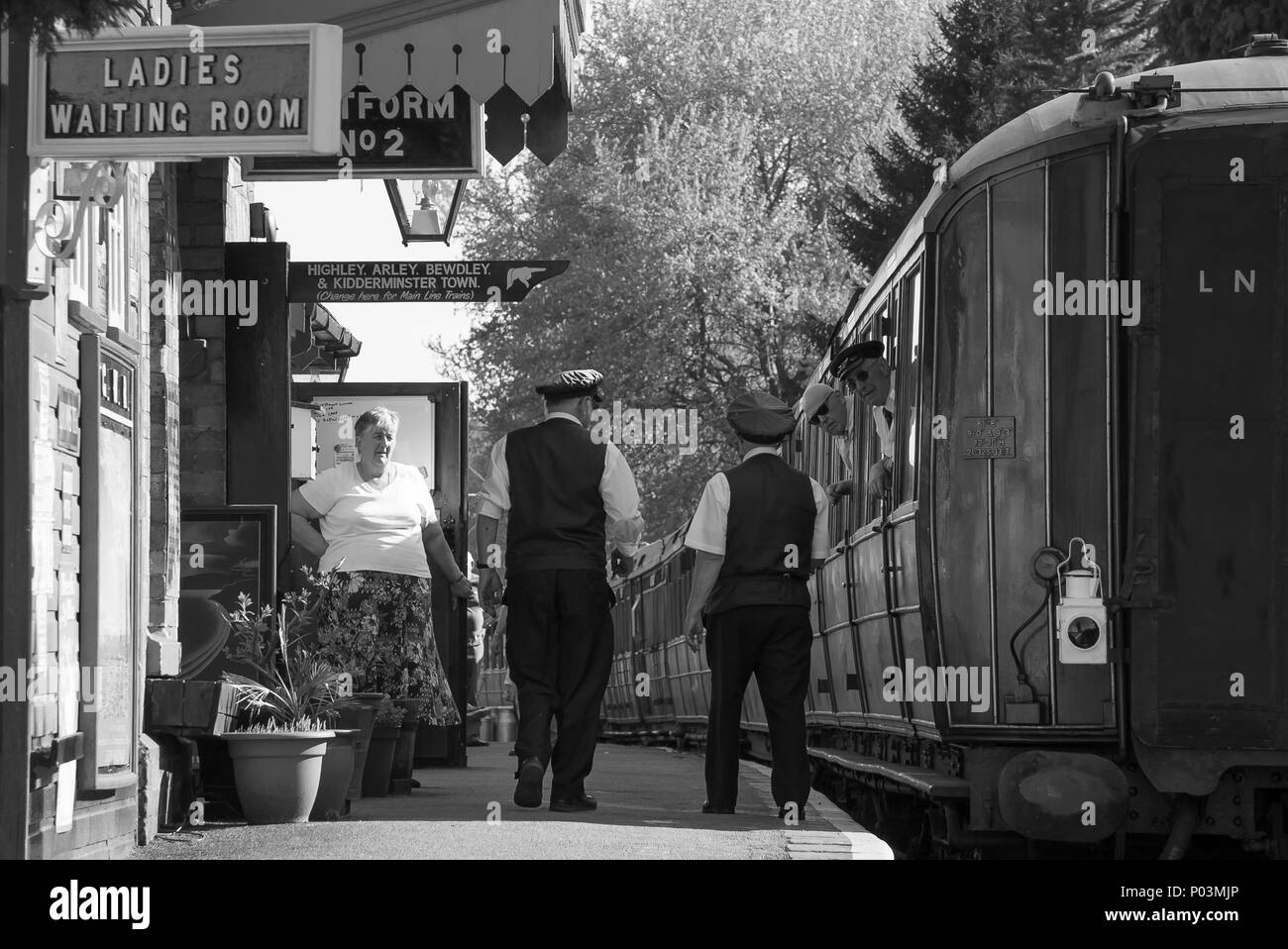 Black & white nostalgia at Hampton Loade station, Severn Valley Heritage Railway, UK. Tea lady greets station master, foreman & guard on train too! Stock Photo