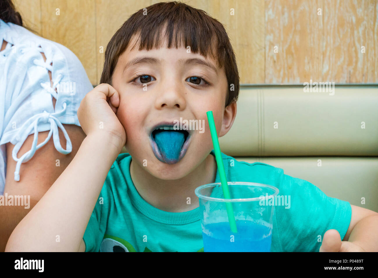 A young child shows his blue tongue after drinking a blue slushy drink Stock Photo