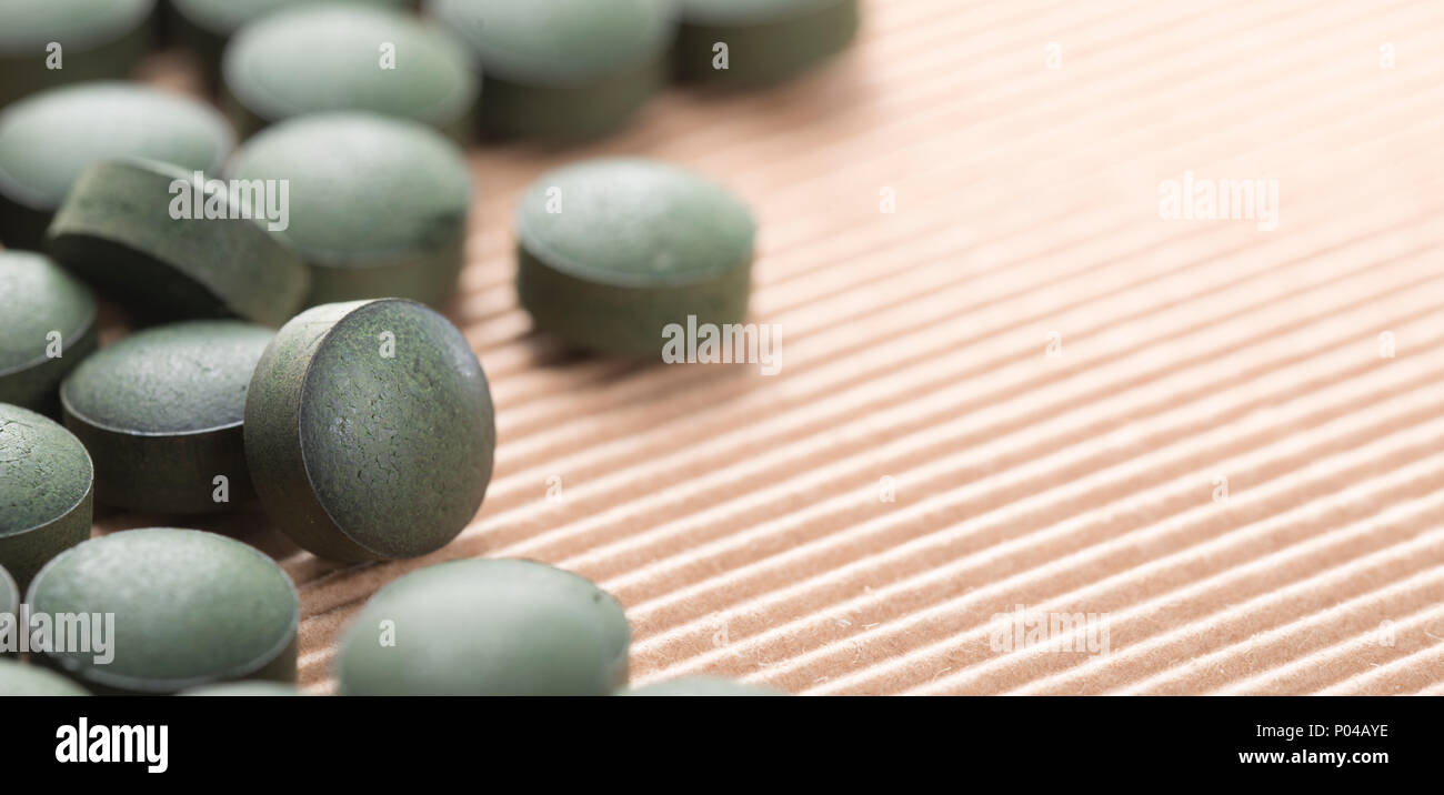 Detail of many organic spirulina tablets with low depth of field over cardboard background. Stock Photo