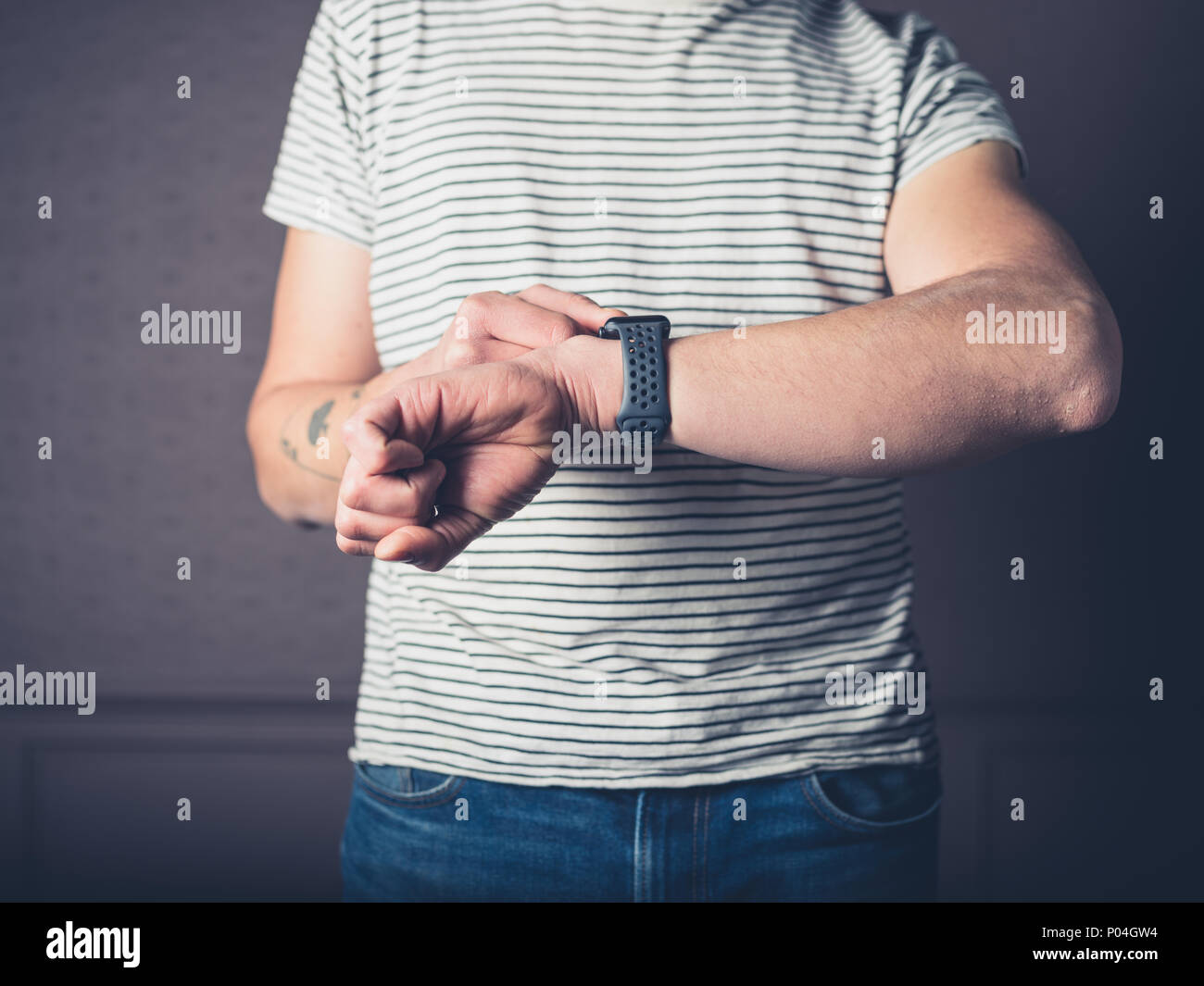 A young man is using his smart watch in a luxury living room Stock Photo