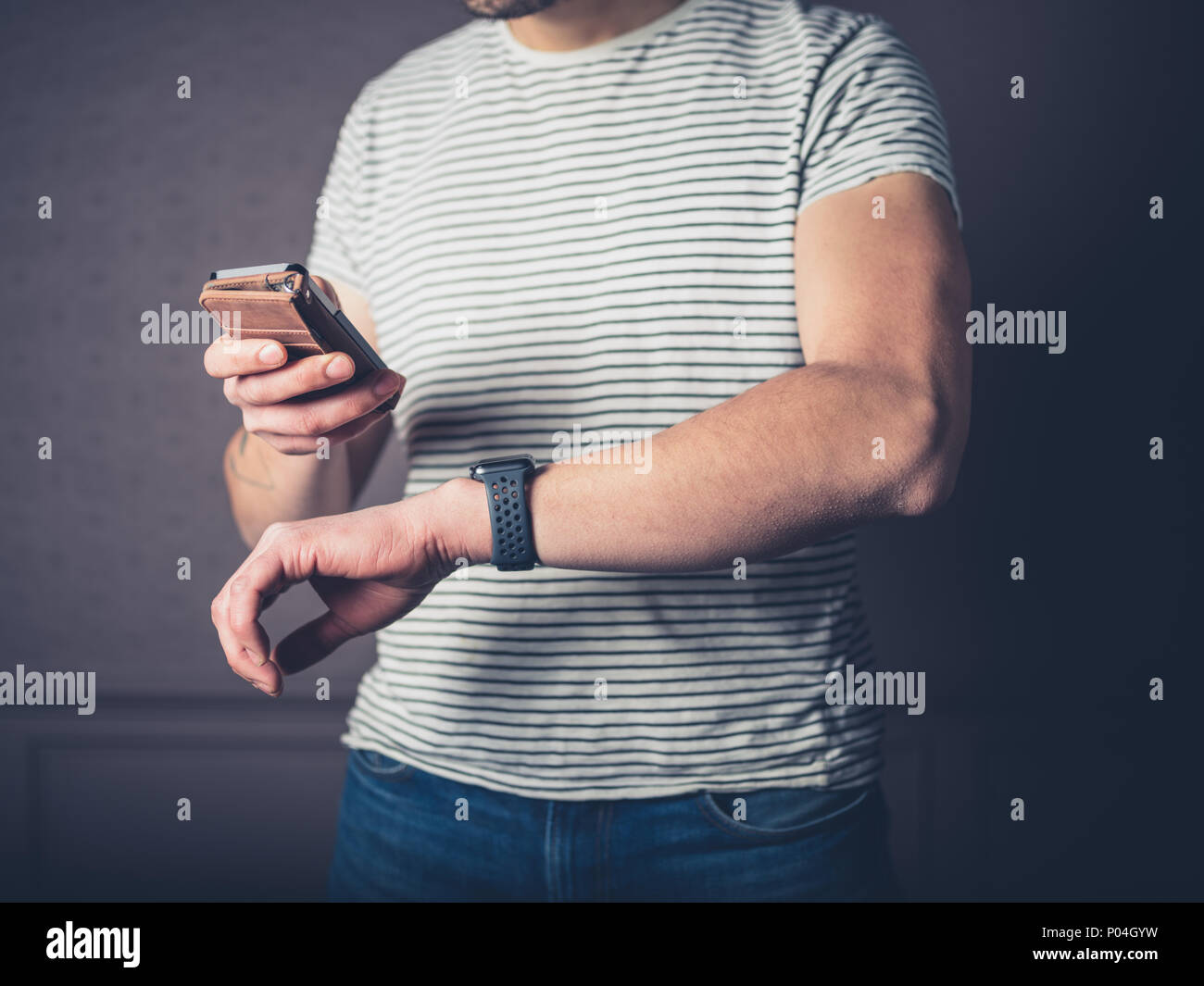 A young man is synching his smart phone and fitness tracker watch Stock Photo
