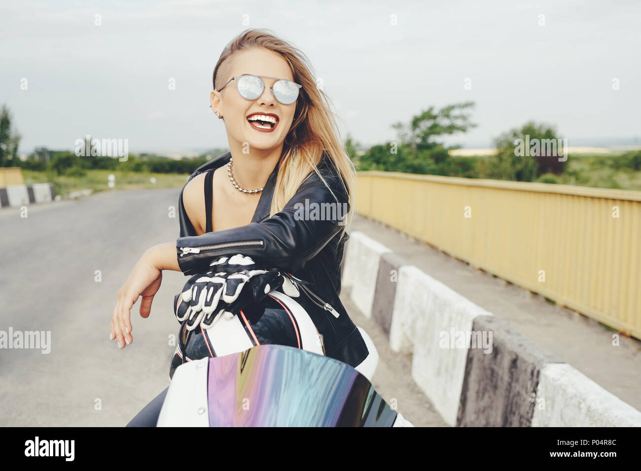 Beautiful woman posing with sunglasses on a motorbike Stock Photo