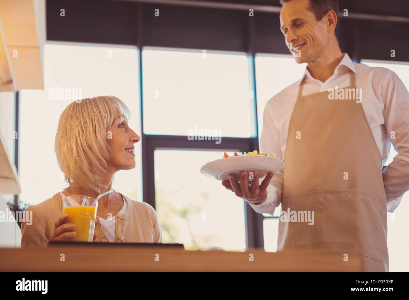Nice service. Handsome young waiter holding an order of his senior ...