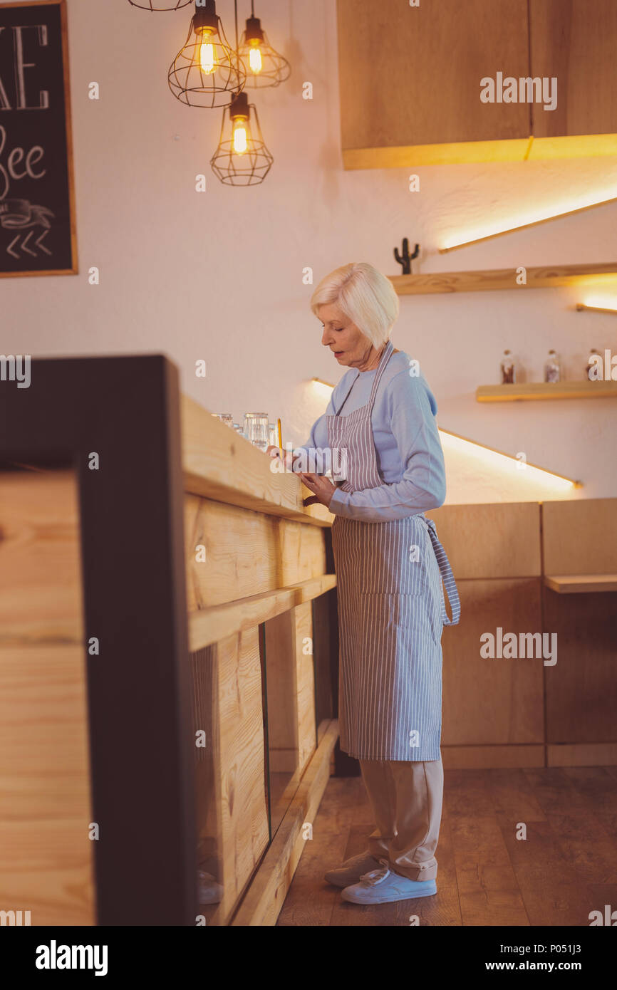 Elderly woman writing while standing behind bar counter Stock Photo Alamy