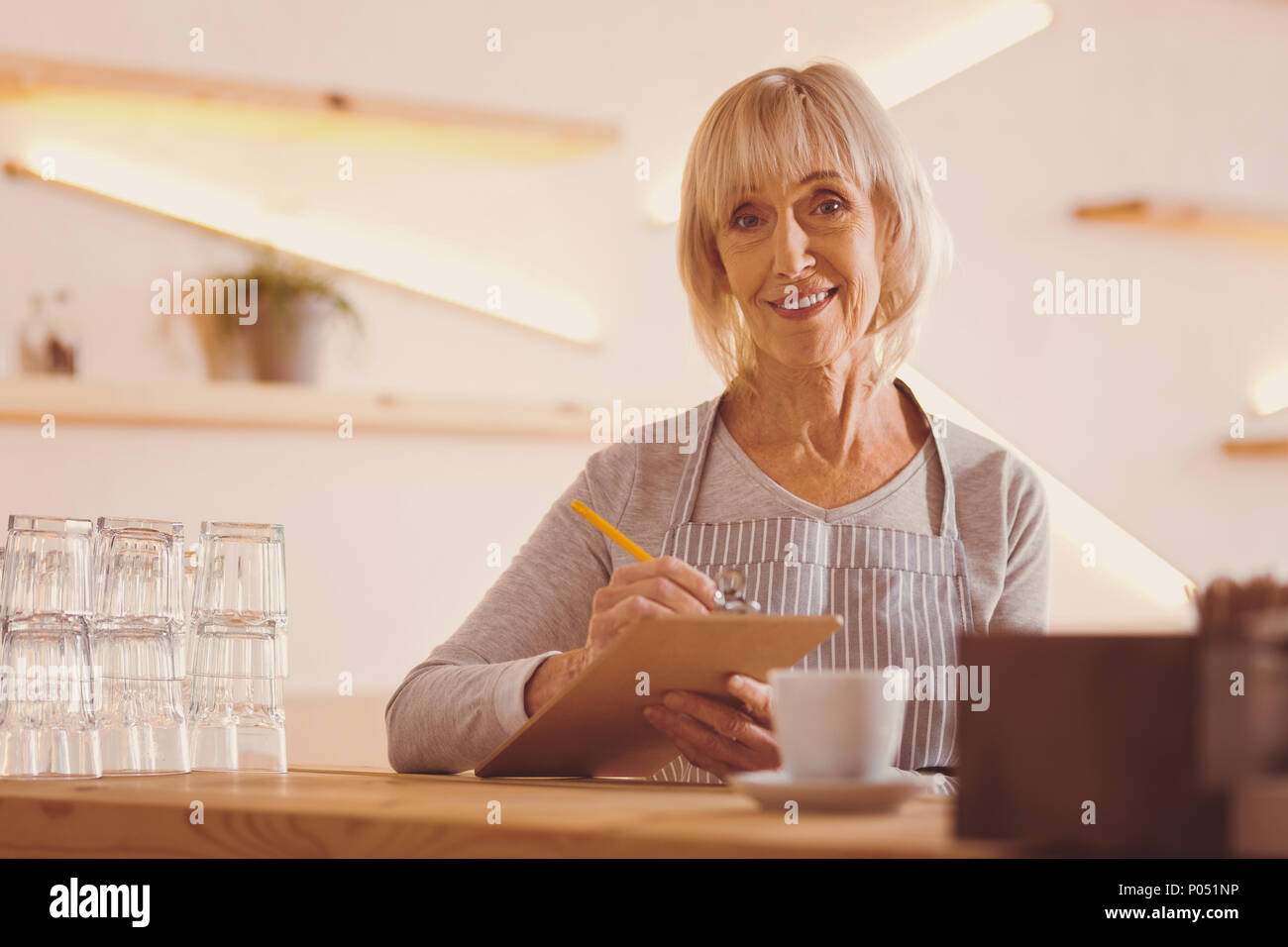 Cheerful woman checking customers orders in her notes Stock Photo