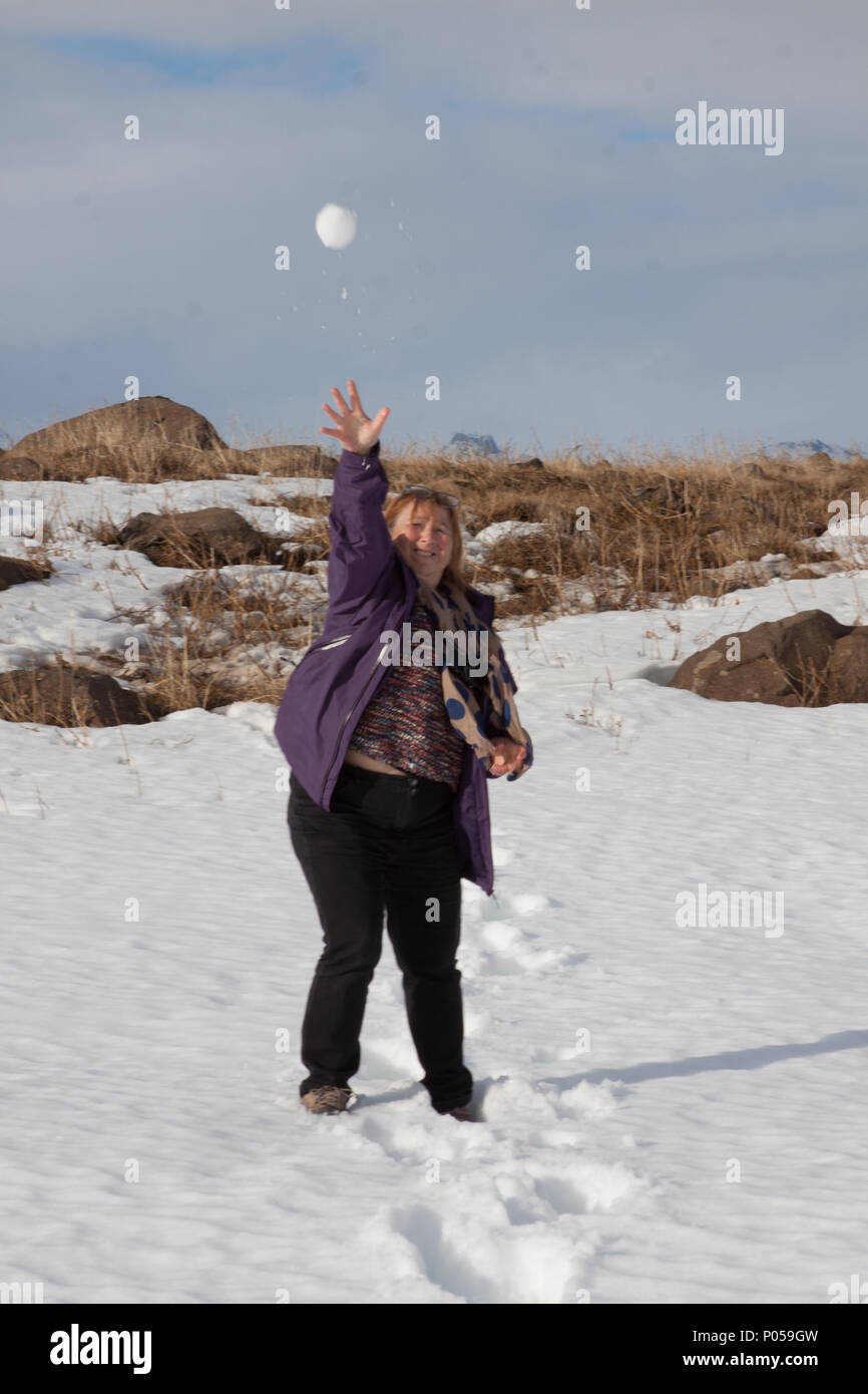 a single women playfully throwing a snowball at the photographer Stock Photo
