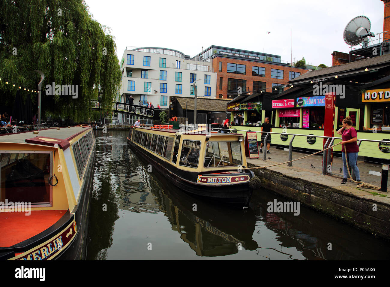 Camden Lock, Woman mooring barge after taking tourists on a boat trip with people walking past market stalls, Camden, London, United Kingdom, 7th June Stock Photo