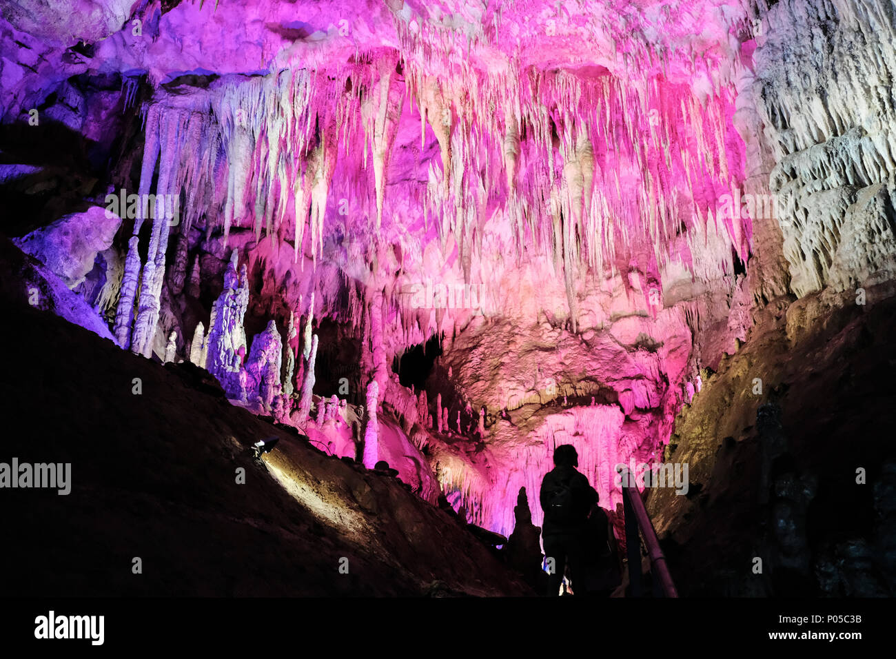 Stalagmites and stalactites are lit up with color in the subterranean ...