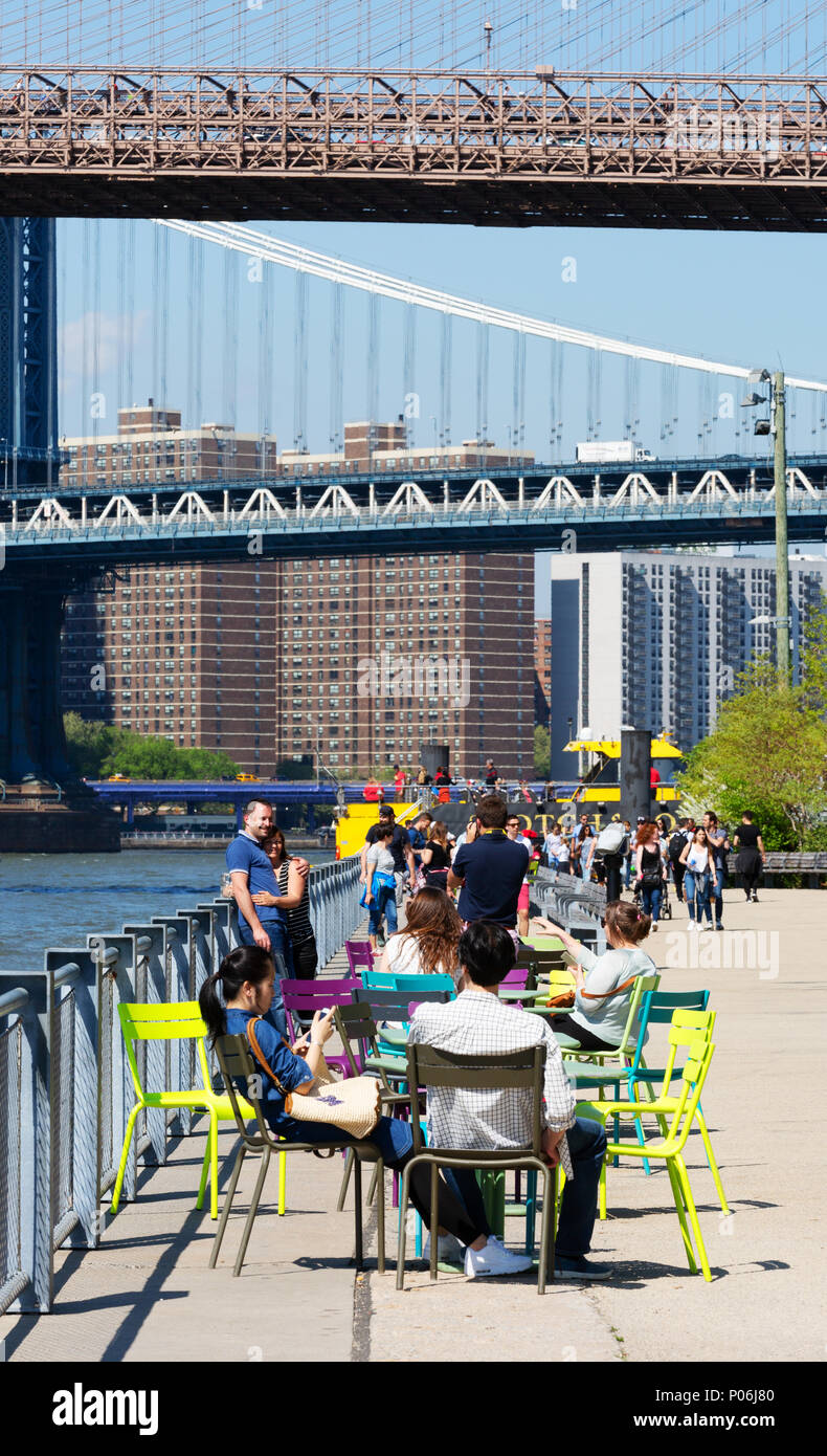 People enjoying the sunshine, Brooklyn Bridge Park with Manhattan bridge in the background, Brooklyn, New York city USA Stock Photo