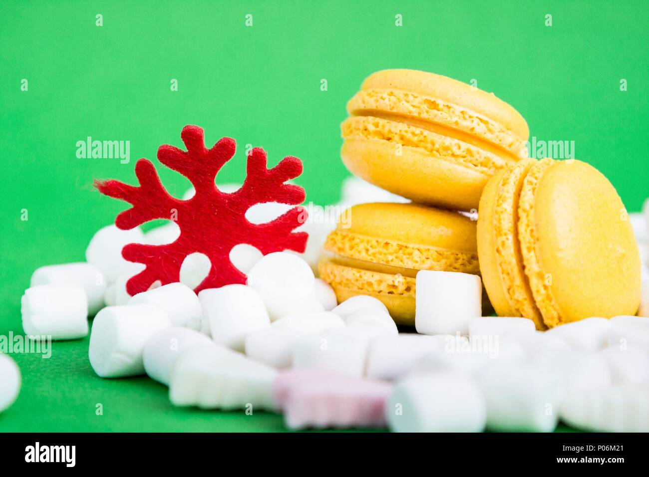Yellow macaroons, marshmallow and red flake on green Stock Photo