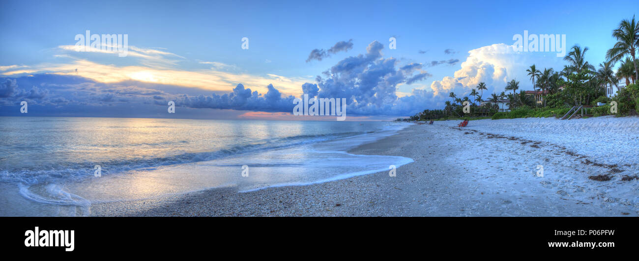 Sunset over ocean on Naples Beach with dark skies overhead and rain on the horizon in Naples, Florida Stock Photo