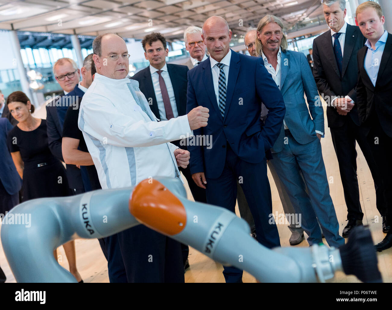 08 June 2018, Germany, Dresden: Albert II, Prince of Monaco (wearing white  jacket) controls the arm of a Kuka robot using a jacket fitted with  sensors, during his visit to the Volkswagen