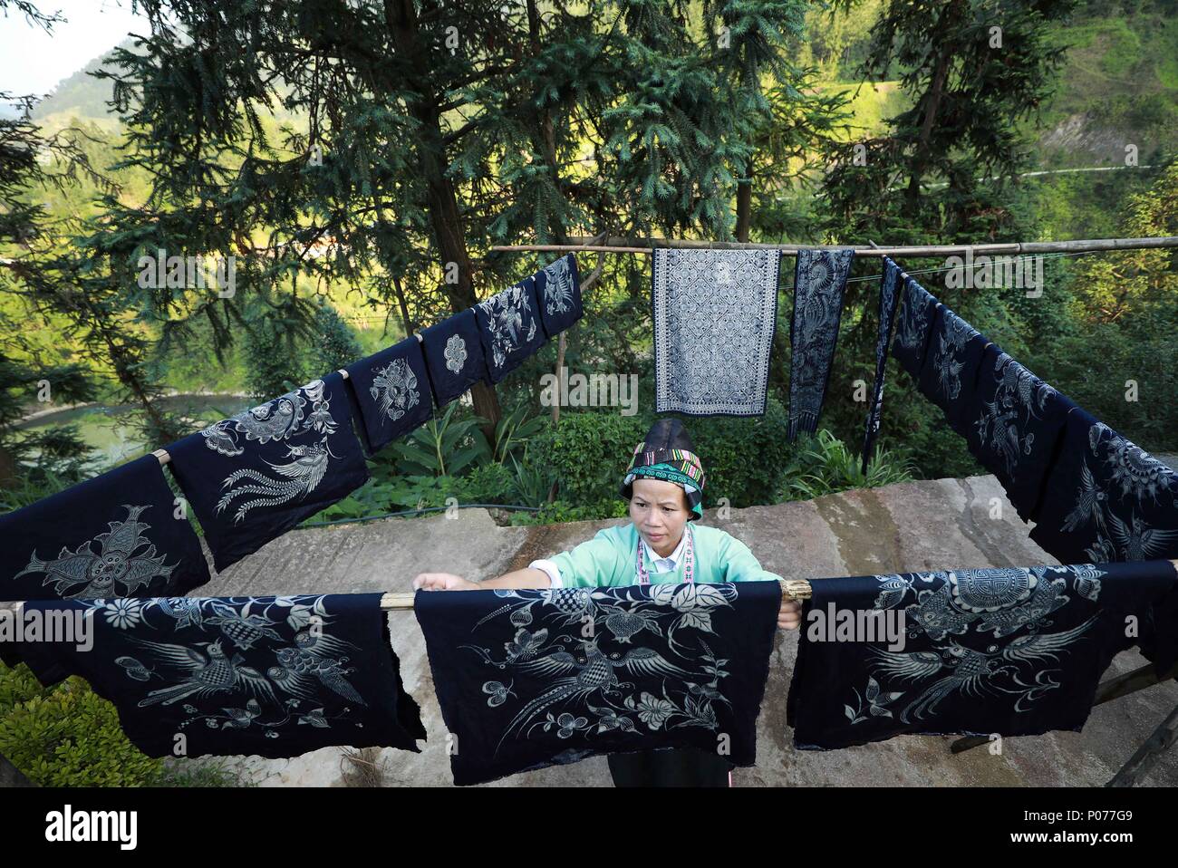 (180609) -- DANZHAI, June 9, 2018 (Xinhua) -- A woman of miao ethnic group dries batik products in Yangwu Town of Danzhai County, southwest China's Guizhou Province, June 8, 2018. Miao people's batik handicraft is one of China's national intangible heritages. As the major inheritance site of Miao people's batik handicraft, Jijia Miao Village of Yangwu Town has a good many excellent craftspeople, but the inconvenient traffic had impeded the sale of batik products to the outside before 2017. With the increasing improvement of traffic and assistance from local government and volunteers since 2017 Stock Photo