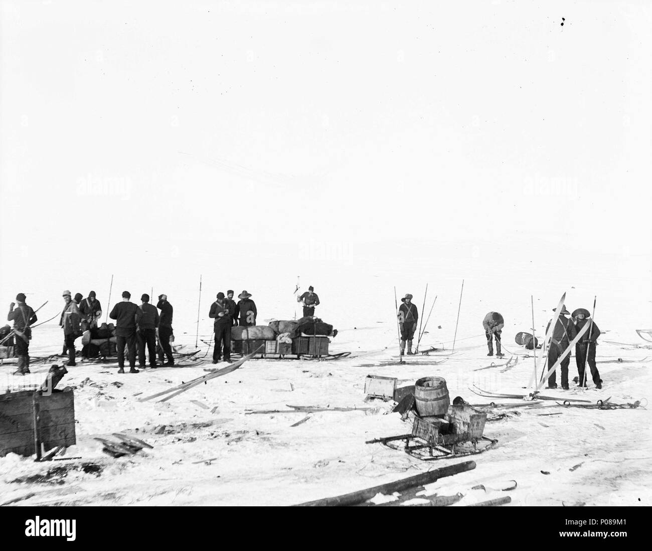 .  English: A general view of sledges, and equipment with crew from Discovery (1901), Terra Nova (1884) and Morning (1871) A general view of the work undertaken to release Discovery (1901), a research/exploration ship, from the ice in the Ross Sea, Antarctica. This was the second relief expedition, and the photograph records a number of aspects of the work to get the ship free. There are two large loaded man-hauled sledges, one flying its sledge flag in the background. A smaller sledge is in the foreground next to an open barrel and discarded equipment. Most of the men are standing by their sl Stock Photo