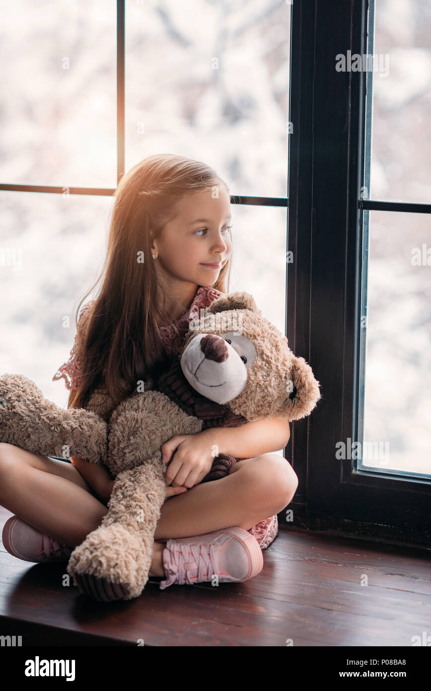beautiful little child sitting on windowsill with teddy bear Stock ...