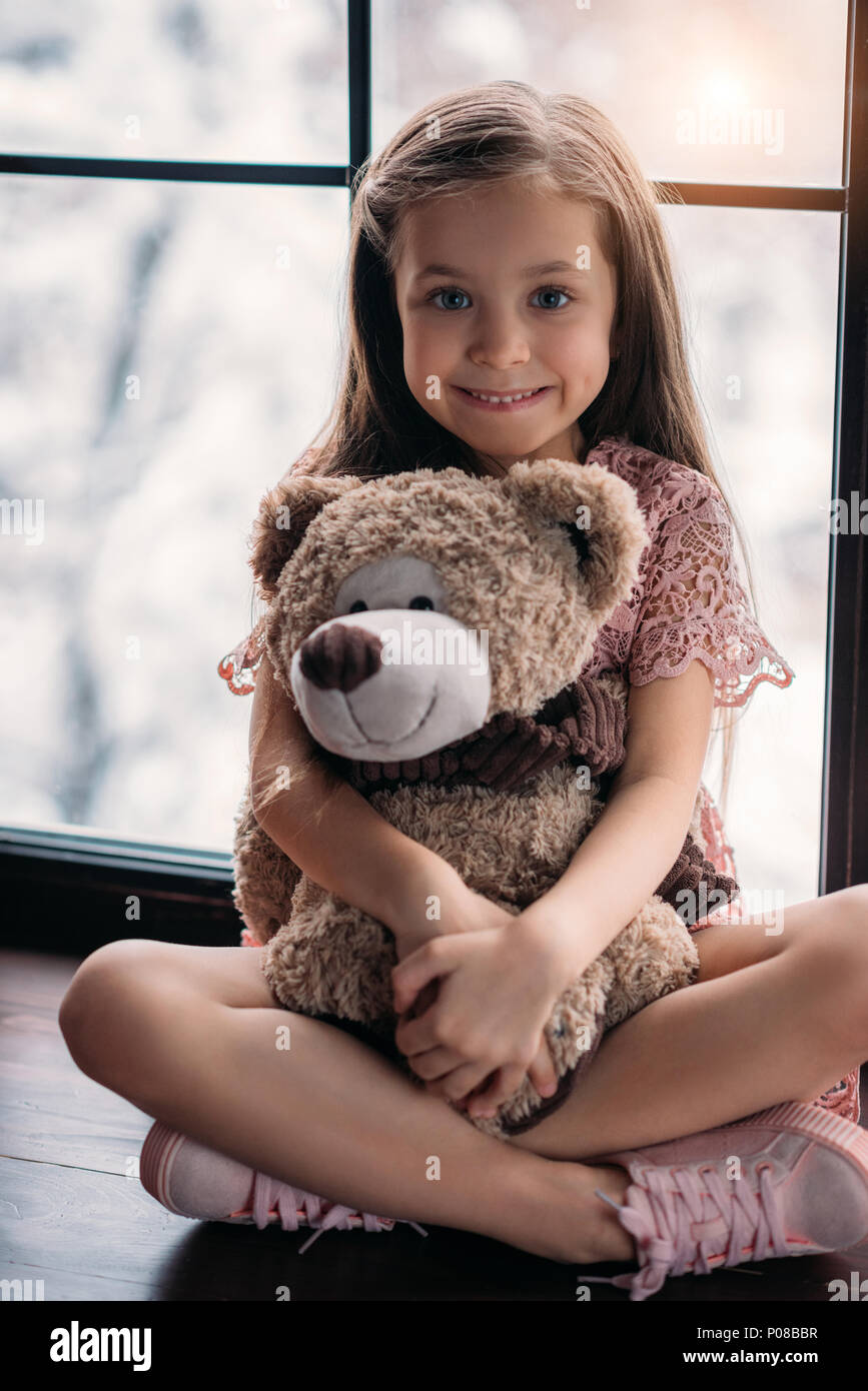 happy little child sitting on windowsill with teddy bear Stock Photo ...