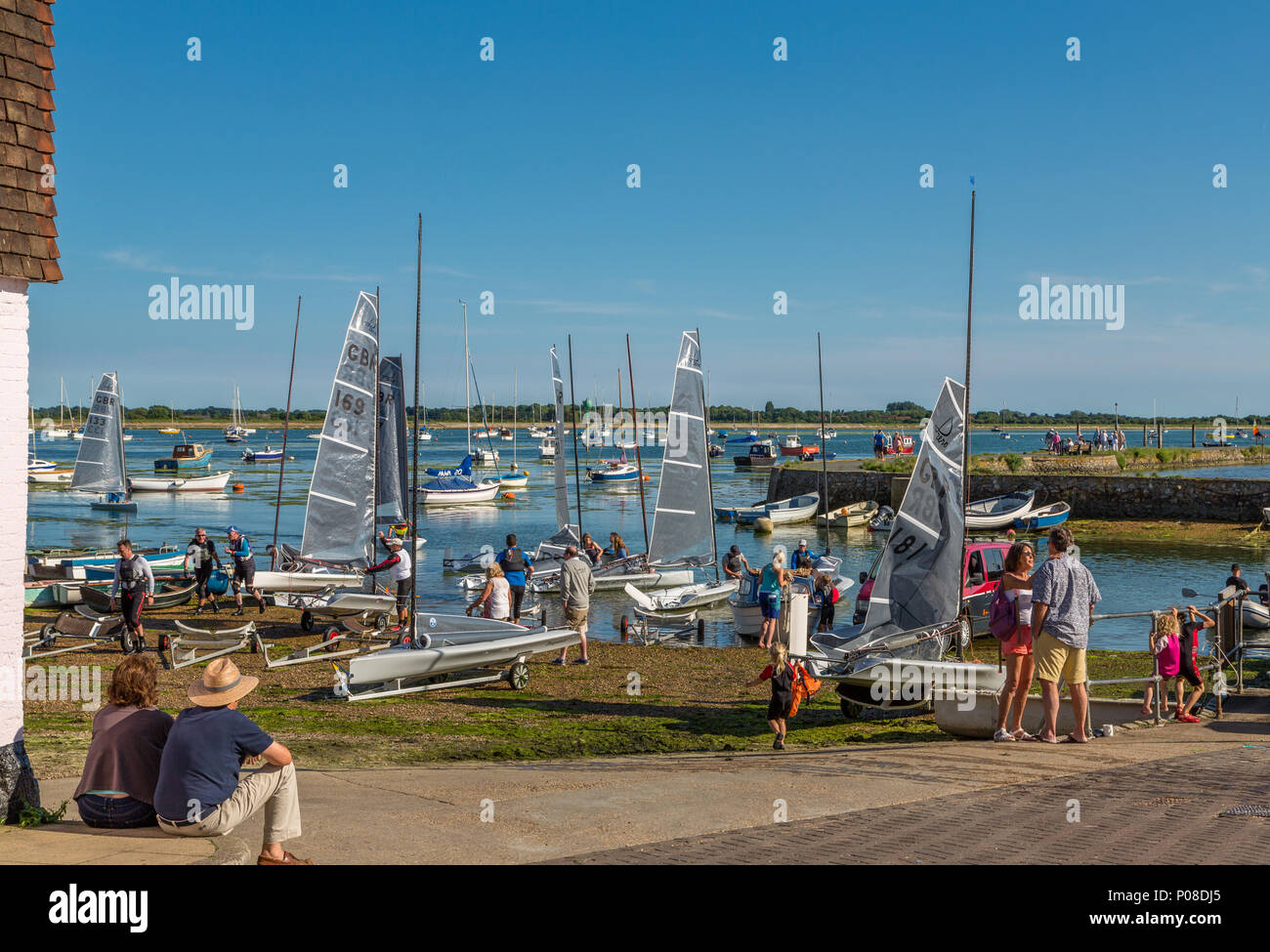 A couple sitting down, look out toward Emsworth basin in Chichester harbour, sailors enjoy warm summer sunshine and fair winds, Emsworth Hampshire UK Stock Photo