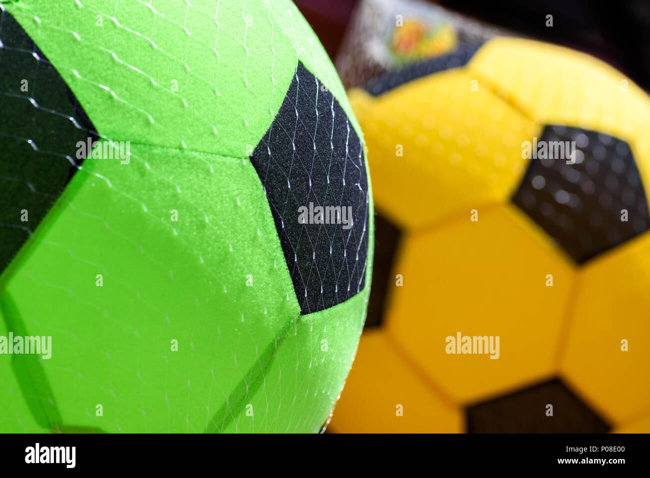 Sponge soccer footballs for sale hanging outside a shop in summer. Stock Photo