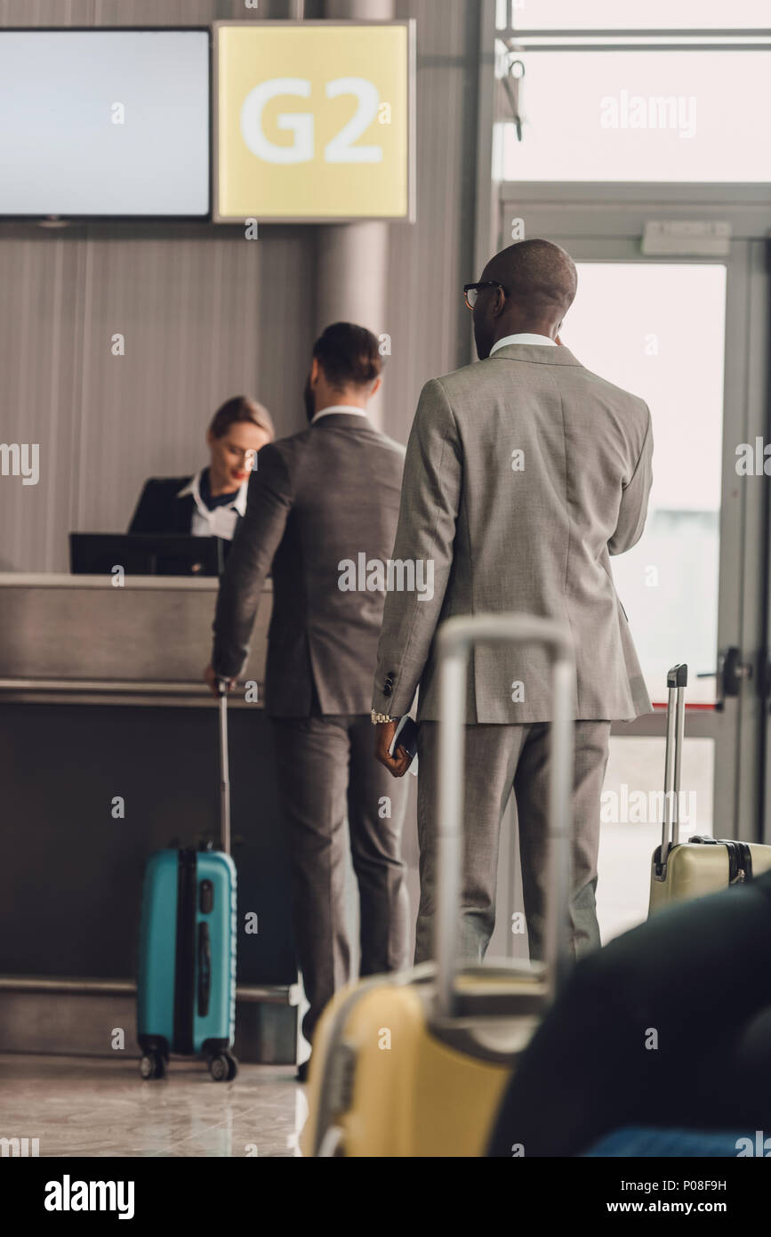 rear view of queue of businesspeople at airport check in counter Stock Photo