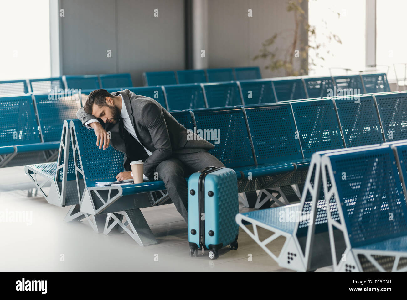 sleepy young businessman waiting for flight at airport lobby Stock Photo