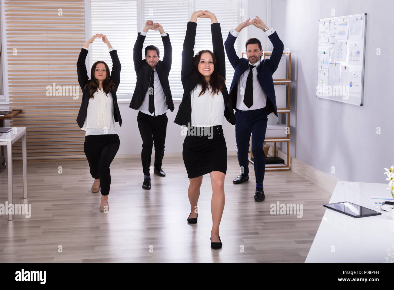 Young Businesspeople Doing Stretching Exercise At Workplace Stock Photo