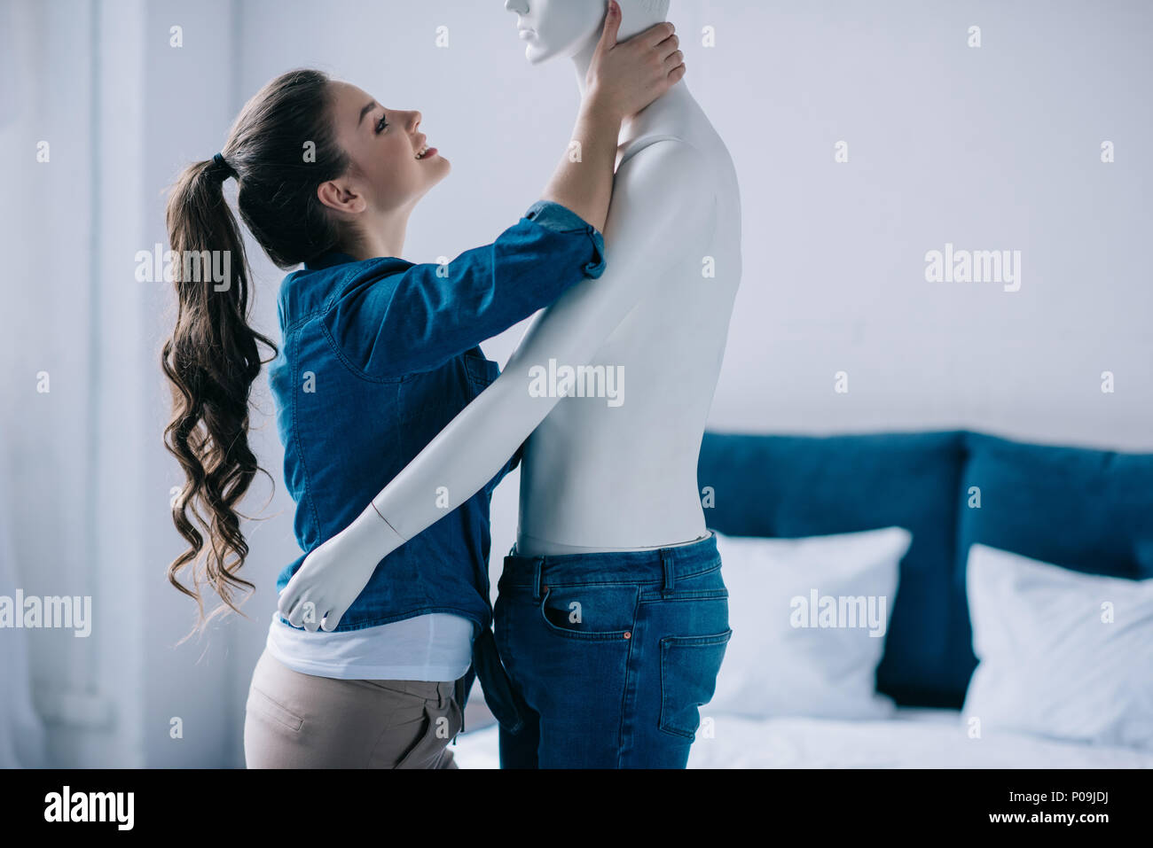 side view of cheerful young woman hugging mannequin, perfect
