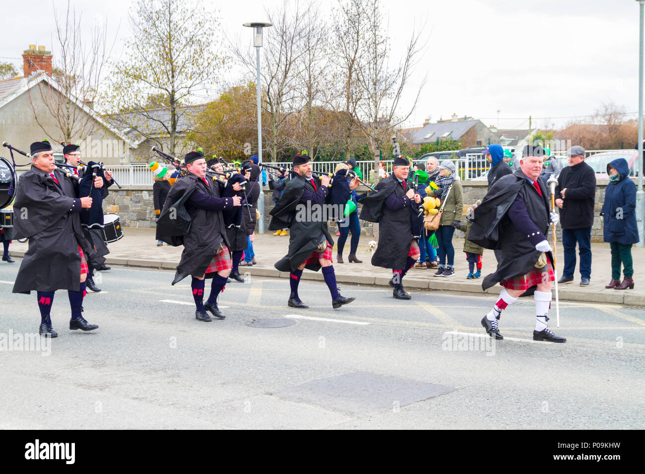 Small local pipe band playing bagpipes and wearing overcoats on a cold