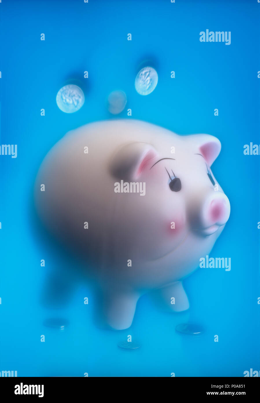 Conceptual image of coins falling from the sky into a piggy bank with a soft ethereal background Stock Photo