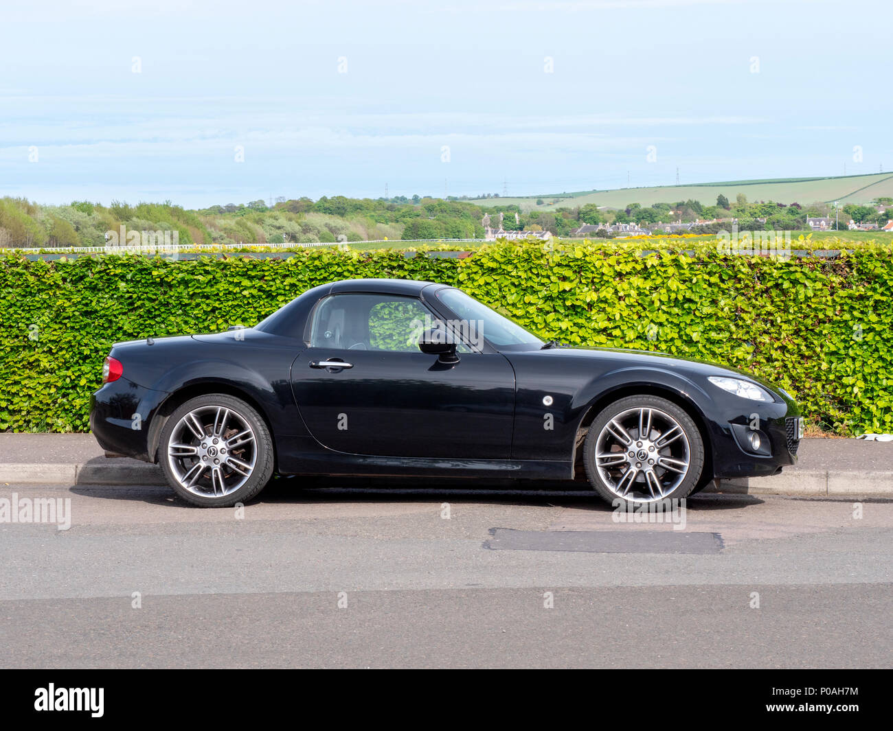 A black, mark three, MX5 car next to a hedge in Musselburgh, East Lothian, Scotland, United Kingdom. Stock Photo