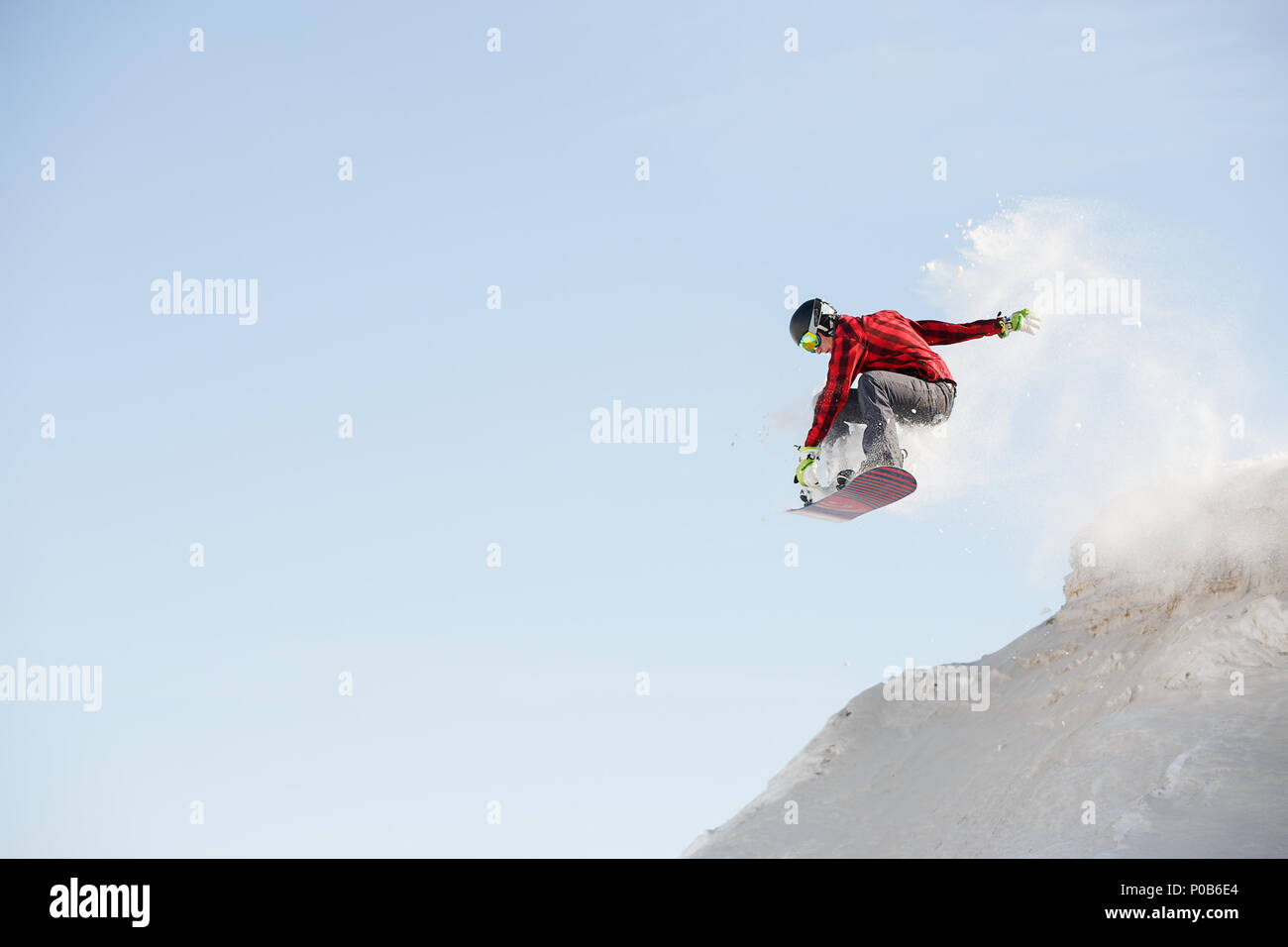 Image of man in helmet with snowboard jumping from snowy mountain slope ...
