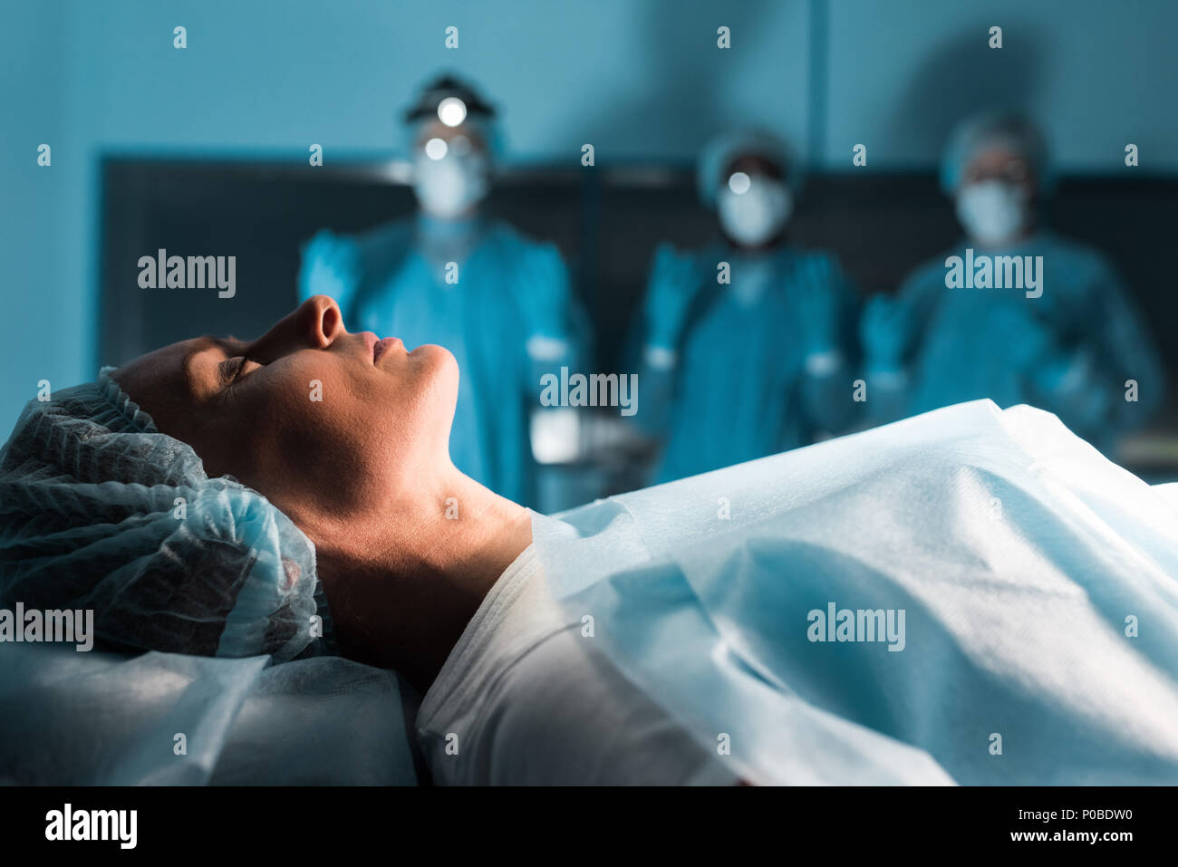 side view of surgeons looking at female patient in operating room Stock ...