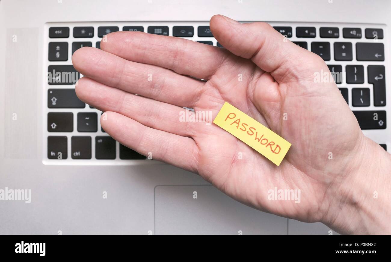 Hand holding note saying Password with keyboard on the background. Stock Photo