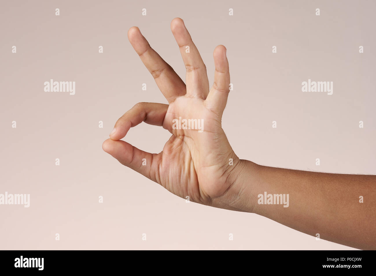 Hand show ok sign isolated on brown background Stock Photo