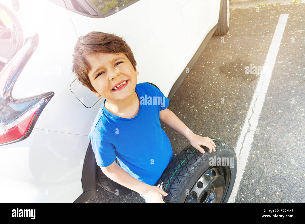 Top view portrait of seven years old boy standing next to the car with