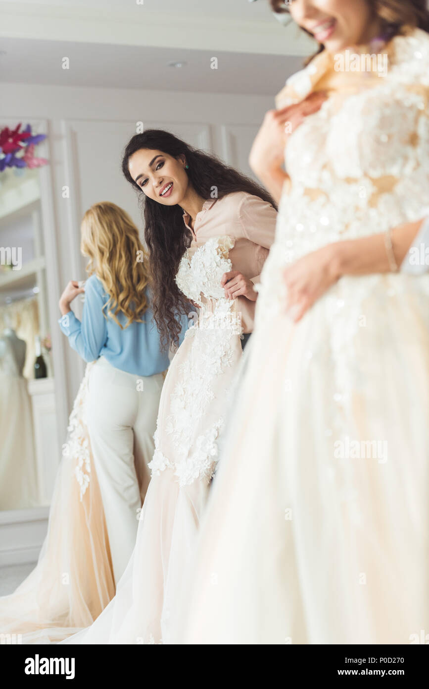 Young smiling bride and bridesmaids choosing dresses in wedding fashion ...