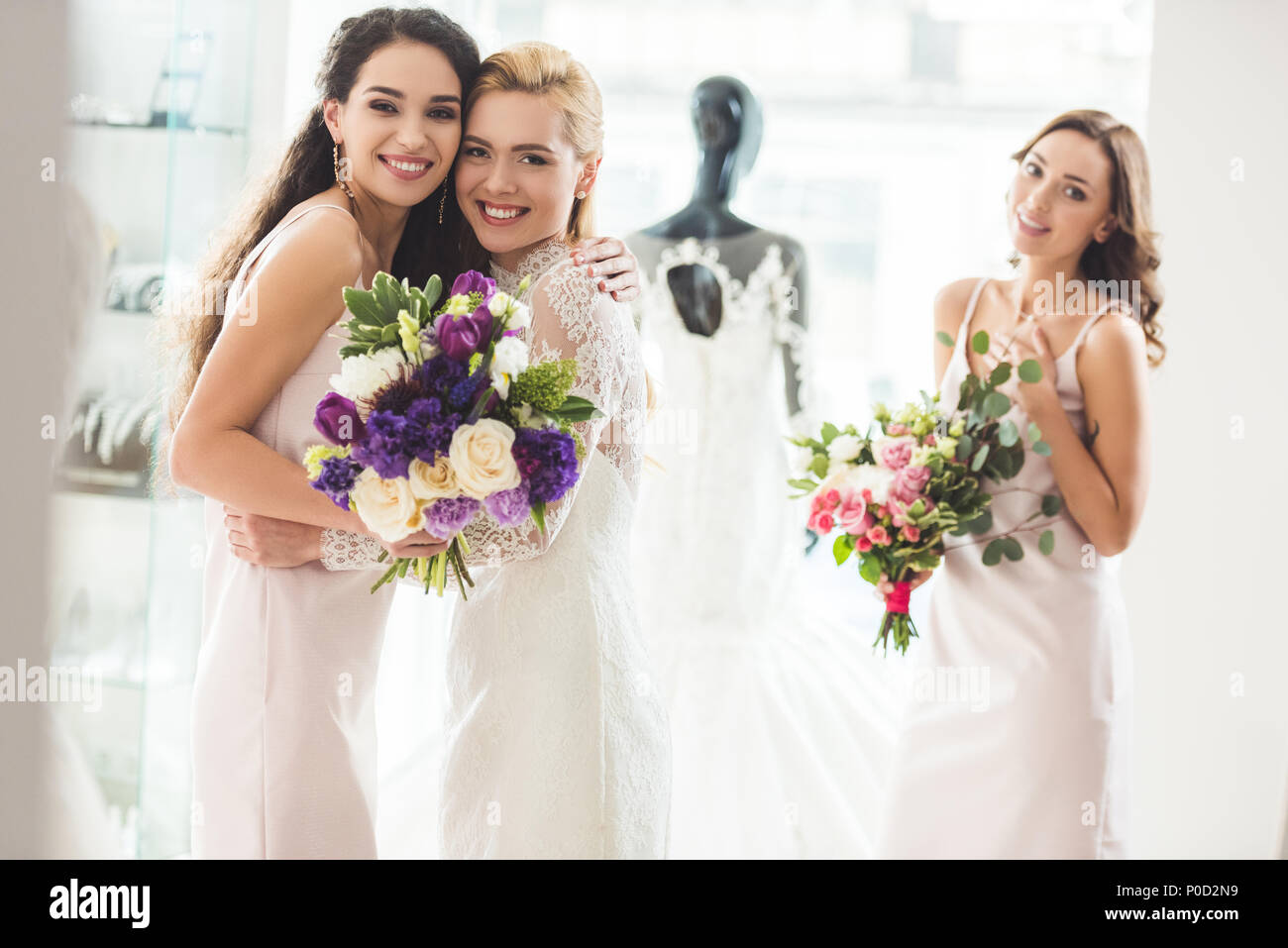 Bride in lace dress and bridesmaids with flowers in wedding salon Stock ...