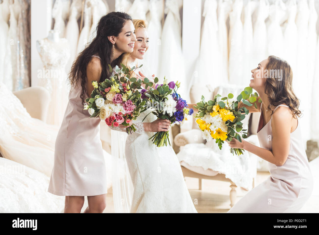 Young bride and bridesmaids holding tender flowers bouquets in wedding ...