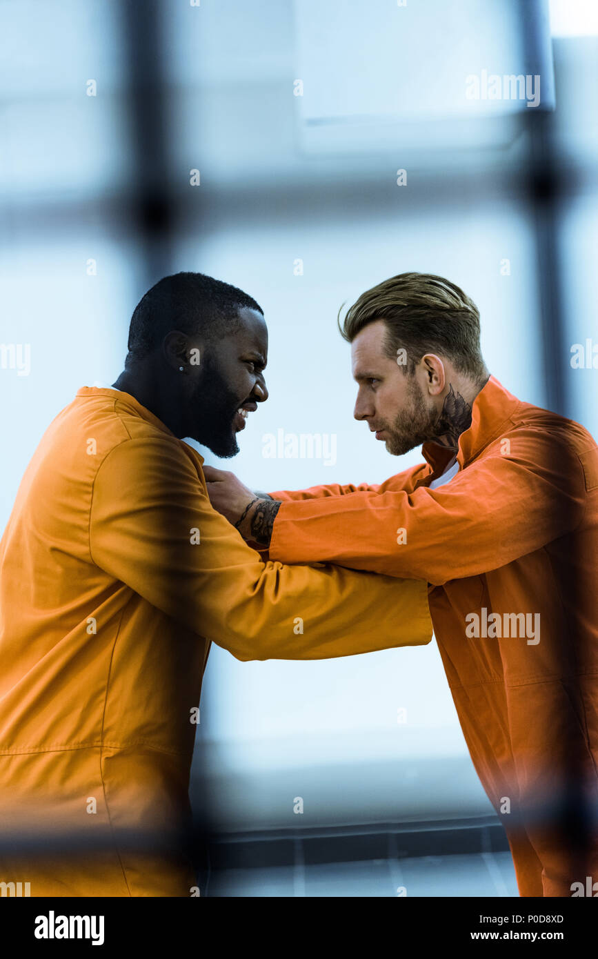 side view of multicultural prisoners threatening each other and holding