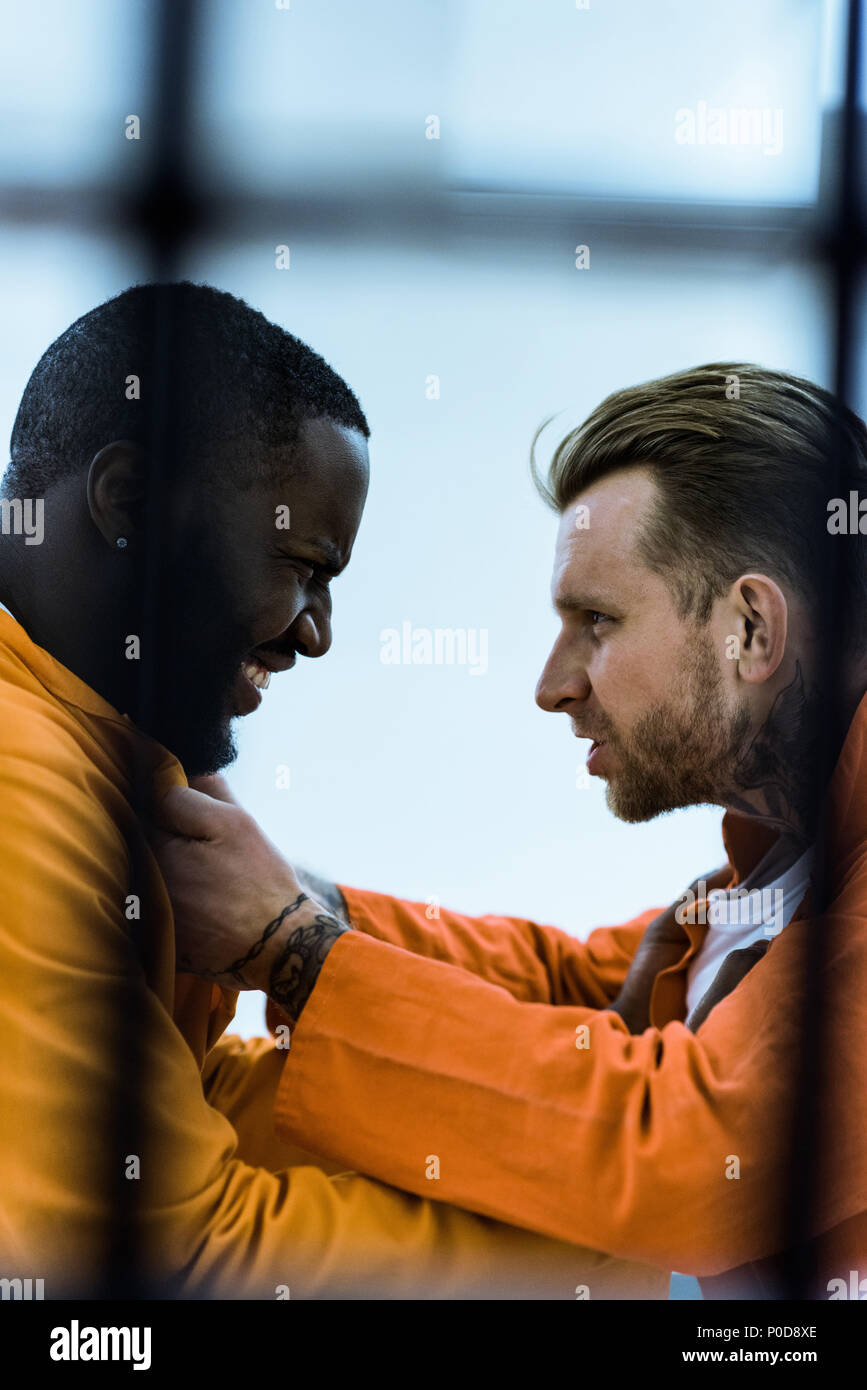 side view of multiethnic prisoners threatening each other and holding