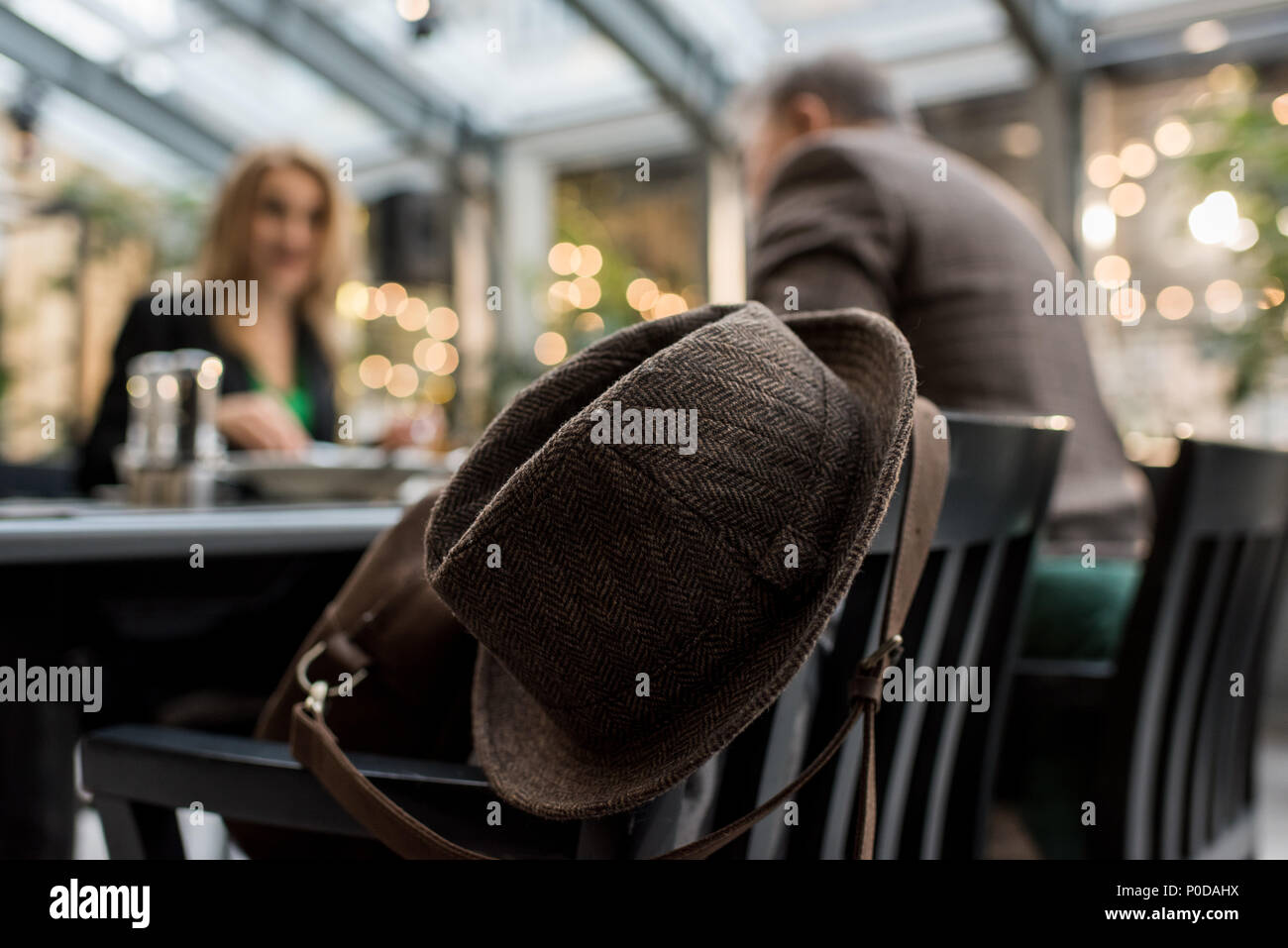 selective focus of hat on chair and couple at table in cafe Stock Photo ...