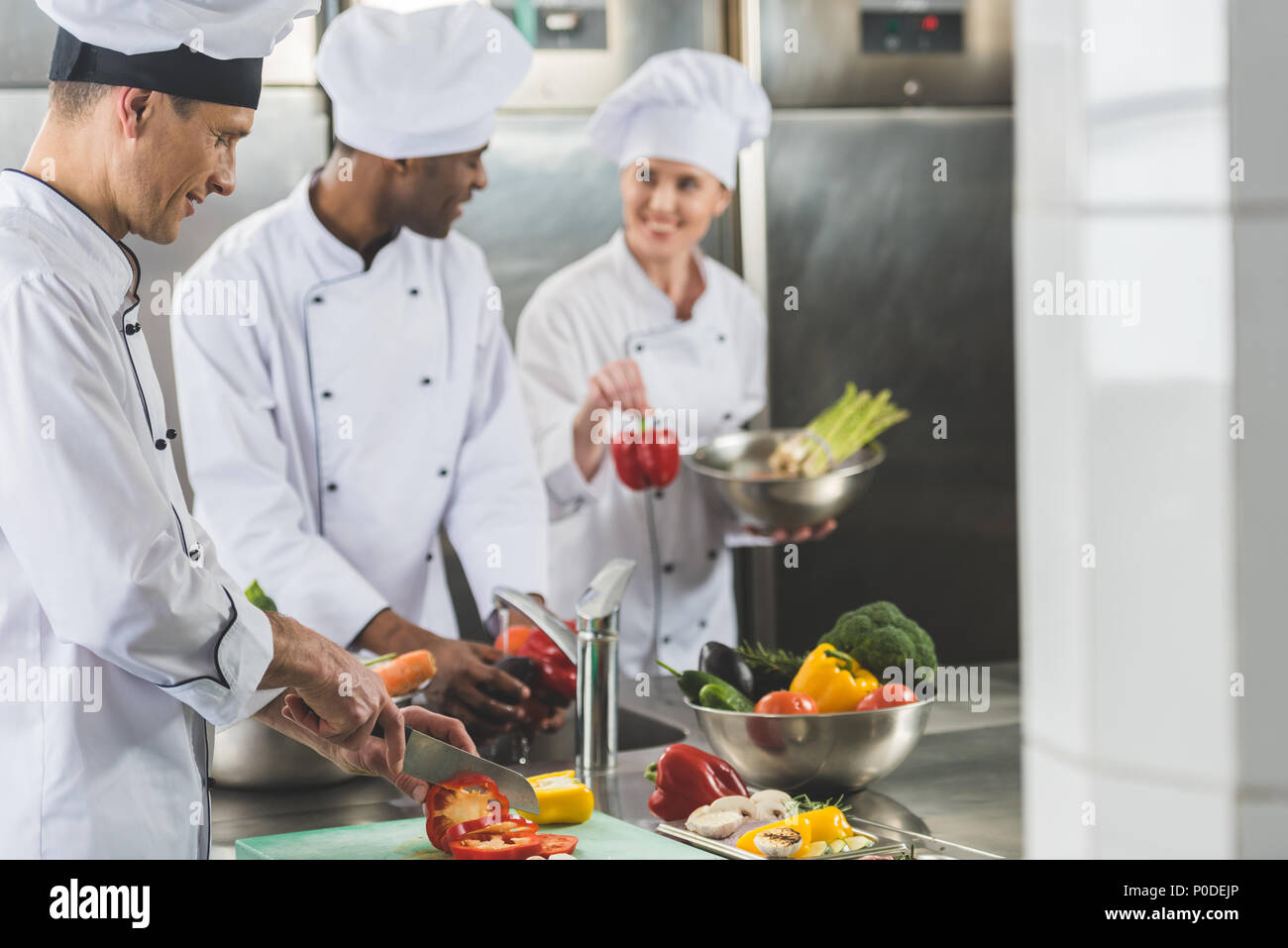 smiling multicultural chefs preparing food at restaurant kitchen Stock Photo
