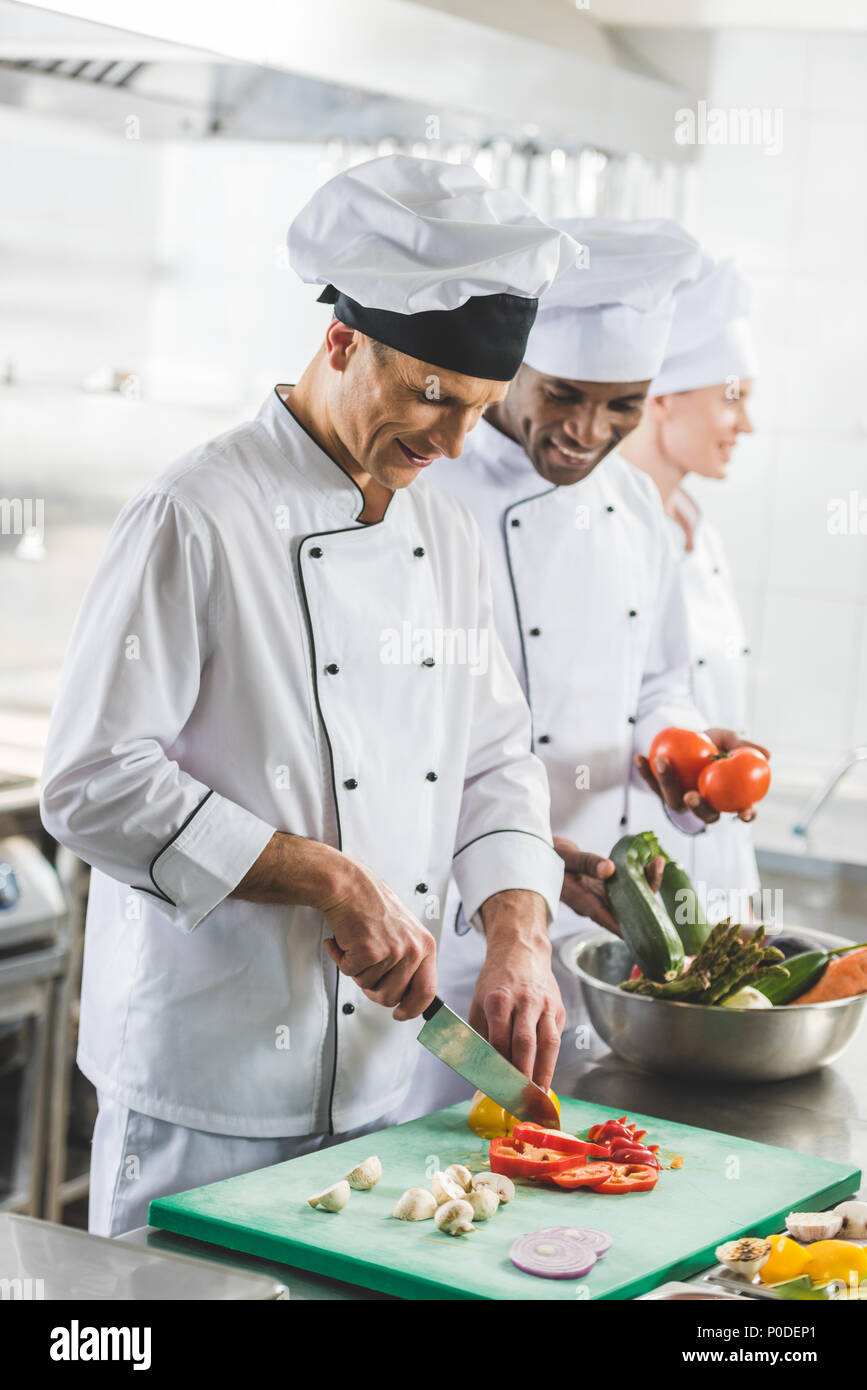smiling multicultural chefs preparing food at restaurant kitchen Stock Photo