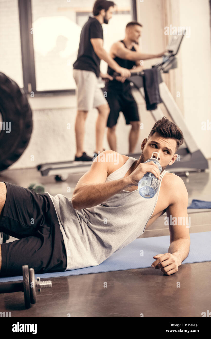 handsome sportsman drinking water from bottle in gym Stock Photo - Alamy