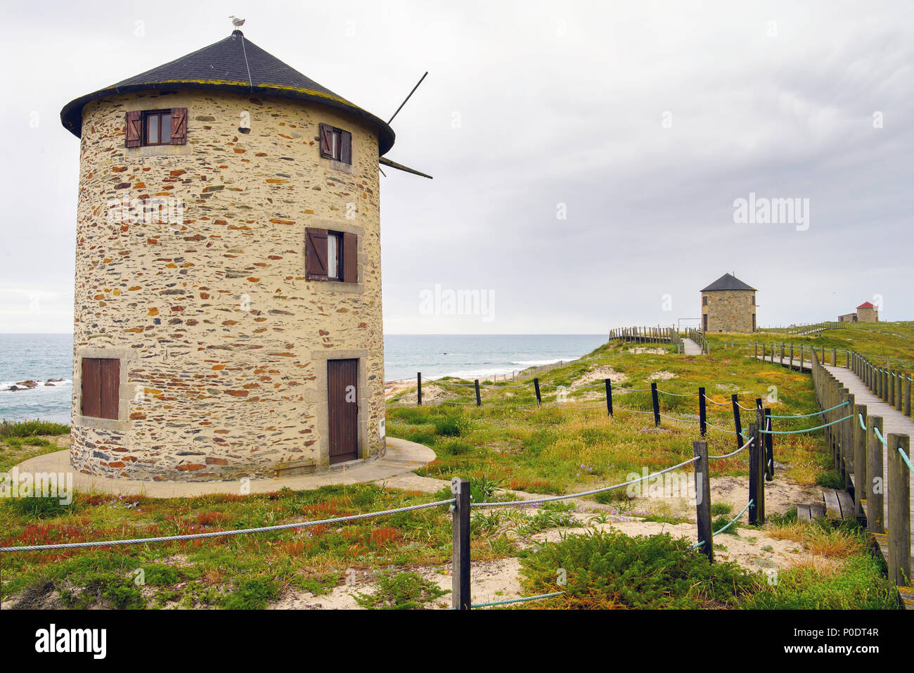 Windmills by the coastal path, beach Praia da Apúlia, Portugal. Stock Photo