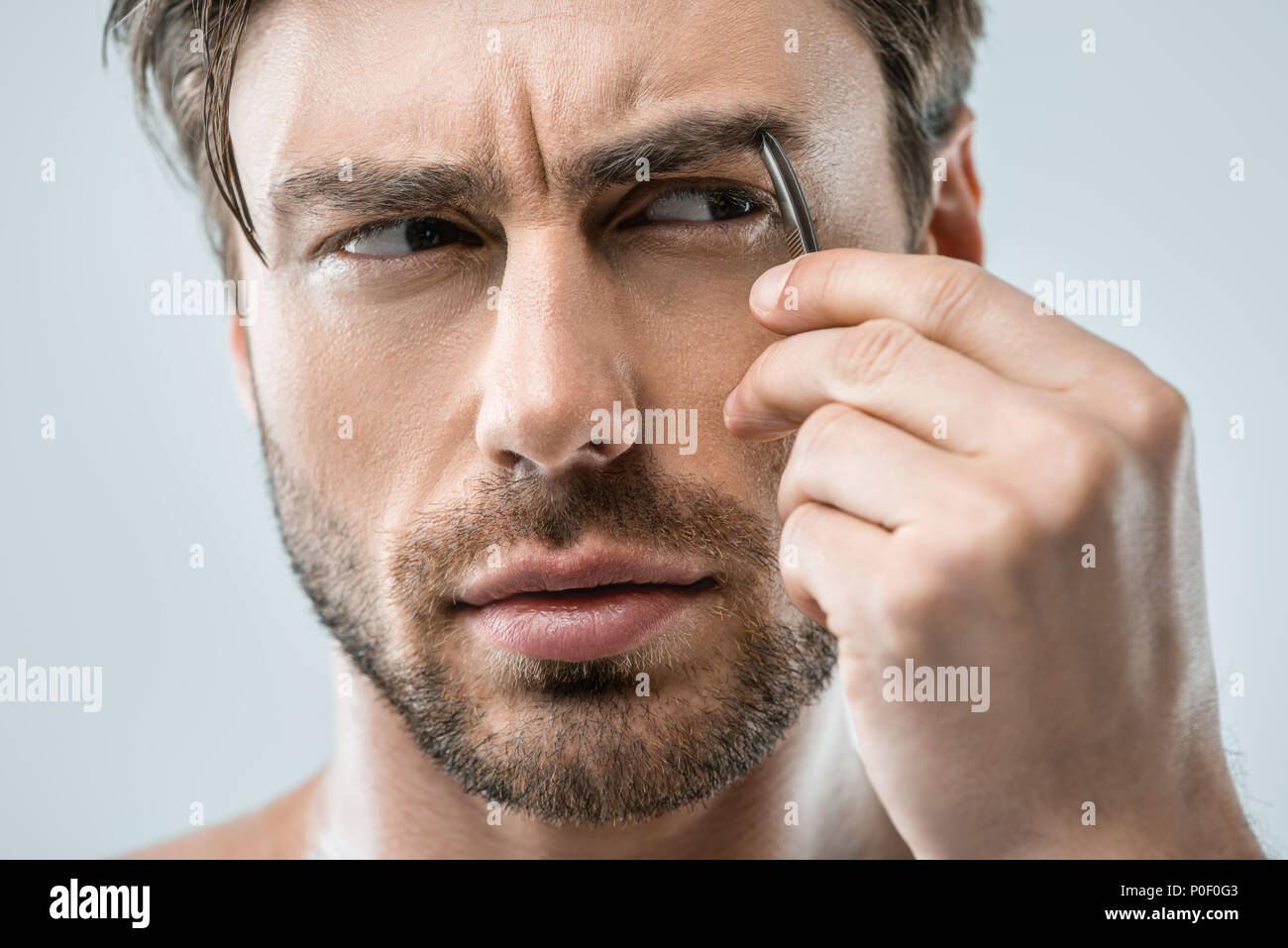 Handsome Man Plucking Eyebrows With Tweezers Isolated On Grey