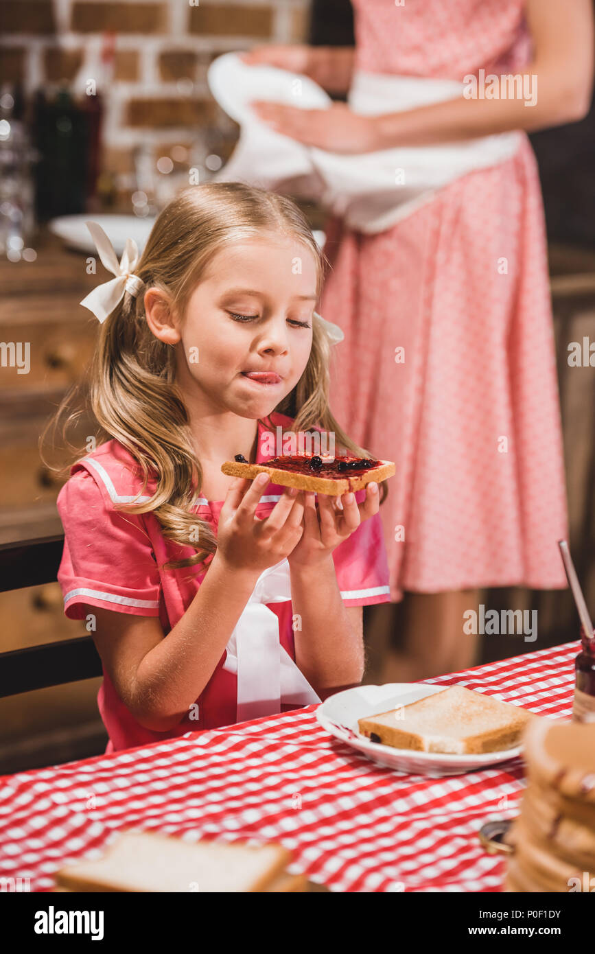 adorable little girl holding delicious toast with jam for breakfast